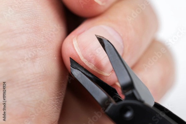 Obraz Nail clipper cutting hand finger isolated on white background