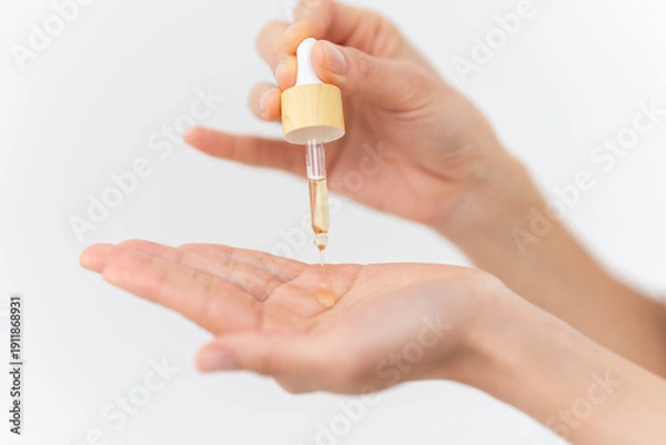 Obraz スキンケアプロセス。美容液を手元に出している女性の手元。