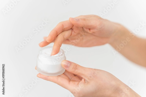 Obraz スキンケアプロセス。ジャー容器からクリームをすくっている手元。