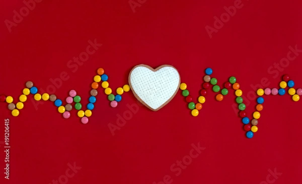 Fototapeta on a red background heart rhythm beats cookies with white mastic music waves radio song souls multi-colored round candies 