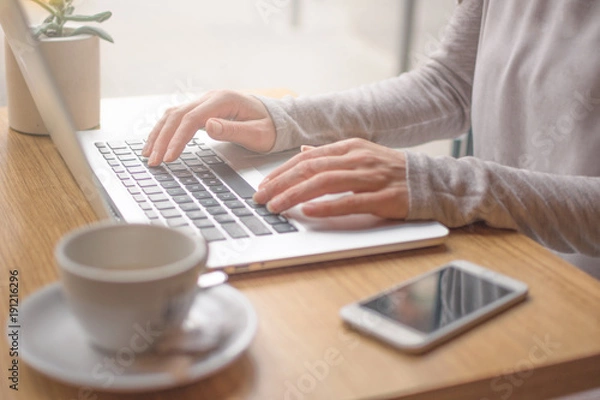 Obraz Woman typing on laptop computer and using smart phone 
