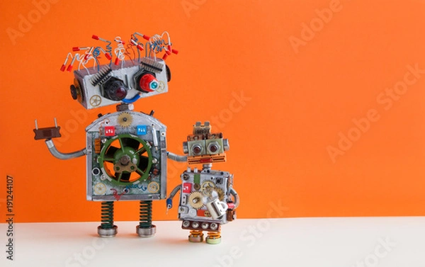Obraz Creative design Robotic family. Big robot electrical wire hairstyle, plug arm. Small kid cyborg with lamp bulb toy. Copy space, orange wall background