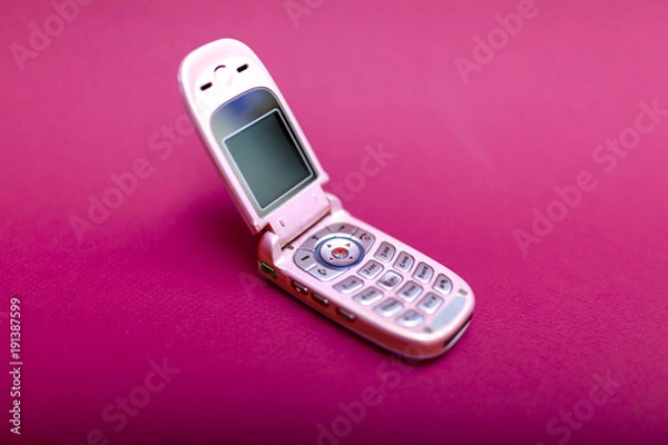 Obraz Cool and classic pink retro flip cell or mobile phone isolated against a red background