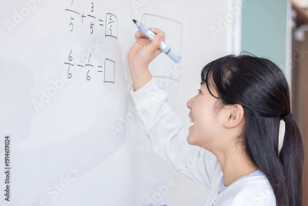 Obraz ホワイトボードに分数を書き込む小学生