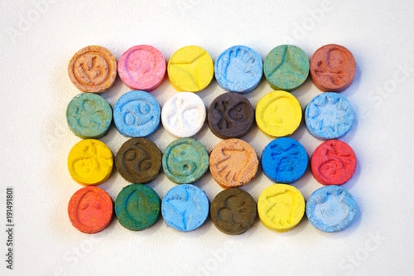 Obraz Kilka pigułek MDMA (Ecstasy) na białym stole rozprowadzanych przez handlarza narkotyków