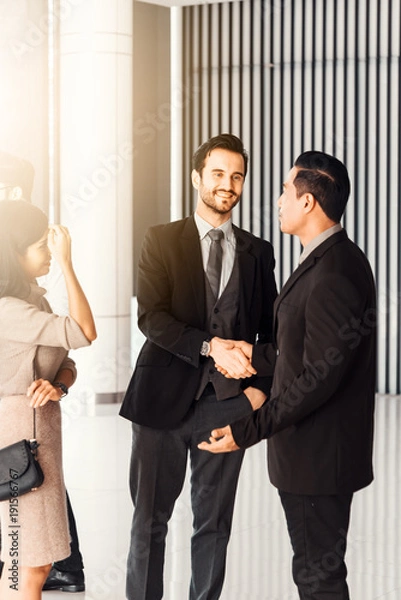 Obraz Corporate teamwork partnership concept . Businessmen presenting and shaking hands to colleagues at office meeting room.