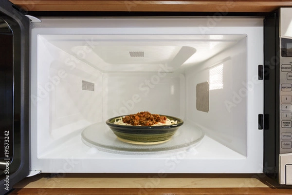 Fototapeta Sprzęt AGD Kuchnia Gotowanie Podgrzewanie Miska Danie Jedzenie Posiłek Kolacja z gotowanego makaronu spaghetti z sosem bolońskim z mięsem pomidorowym w kuchence mikrofalowej