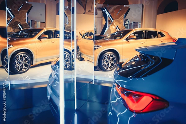 Fototapeta fashionable bright auto show A number of new cars parked in the car dealers' warehouse, modern design of the room with mirrors