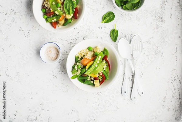 Fototapeta Pearl couscous with fresh vegetables bowl. Young green peas pod, corn, baby carrots, spinach, beans. On a light background. Food concept.