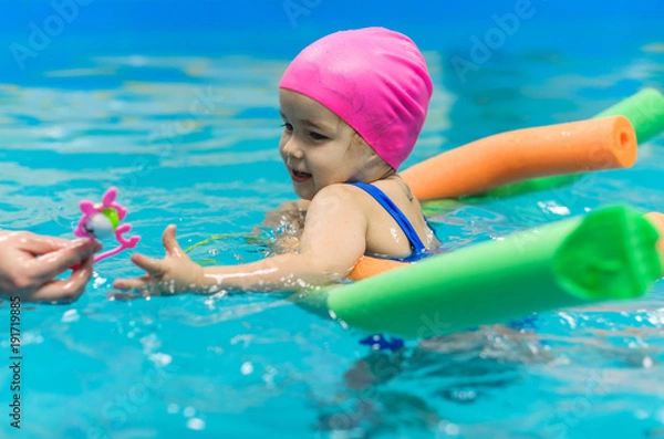 Fototapeta A little girl of European appearance floating in the pool on inflatable toy
