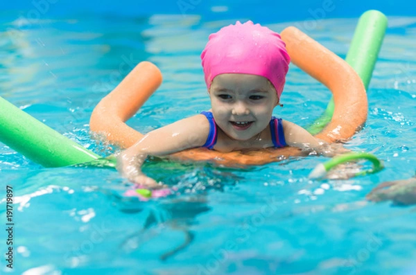 Fototapeta A little girl of European appearance floating in the pool on inflatable toy