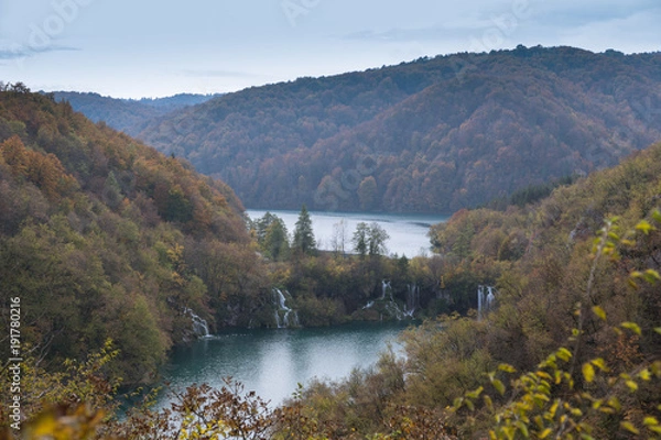 Obraz A fall afternoon with changing colors and multiple waterfalls in the distance. The weather is overcast.