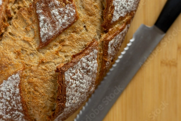 Obraz rustic sourdough bread with bread knife on cutting board close-up