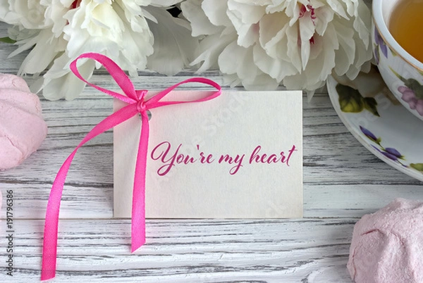 Fototapeta Valentines day greeting card with white peonies tea cup marshmellow and lettering.