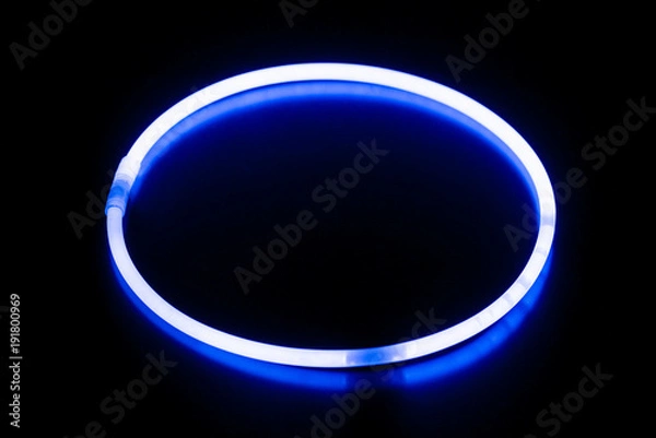 Obraz Okrągła niebieska bransoletka ze świecącym sztyftem / Okrągła niebieska bransoletka ze świecącym sztyftem na czarnej powierzchni z odbiciem