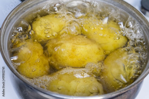 Fototapeta Untreated potatoes boil in a pot on a gas stove.