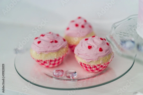 Fototapeta three pink muffins with red hearts on a transparent plate