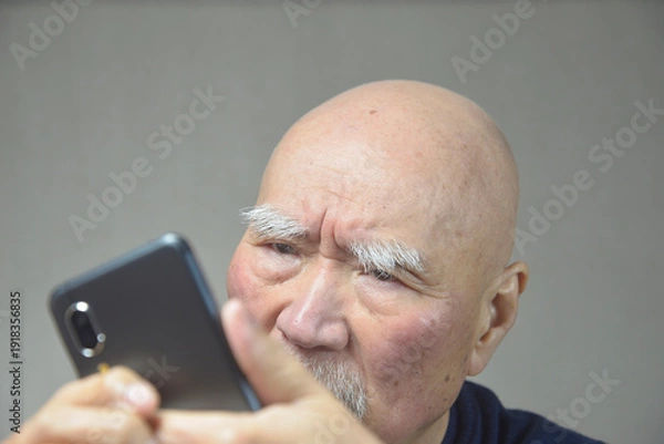 Obraz スマートフォンを操作する老人