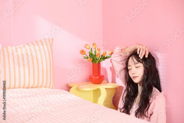 Obraz ピンク背景の部屋でリラックスするアジアの若い女性のポートレート