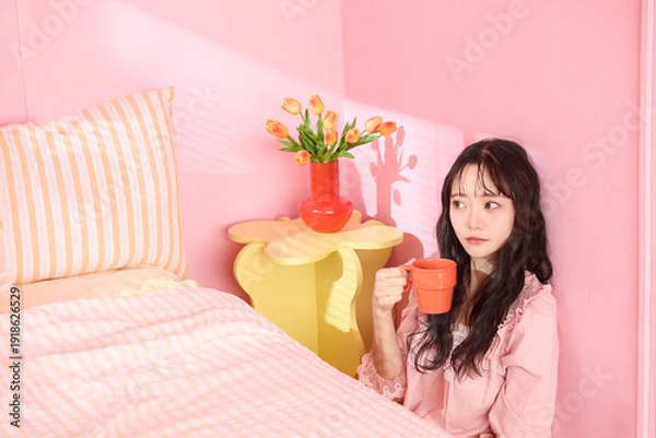 Obraz ピンク背景の部屋でリラックスするアジアの若い女性のポートレート