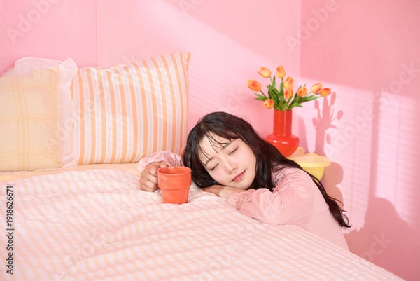 Obraz ピンク背景の部屋でリラックスするアジアの若い女性のポートレート