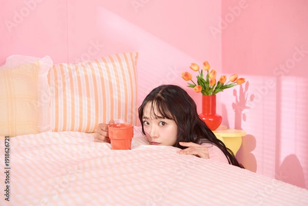 Obraz ピンク背景の部屋でリラックスするアジアの若い女性のポートレート