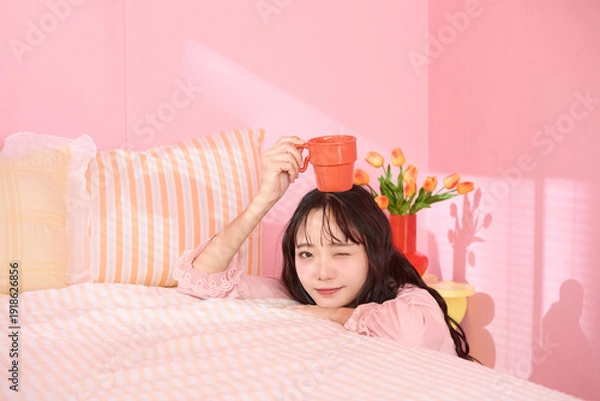 Obraz ピンク背景の部屋でリラックスするアジアの若い女性のポートレート