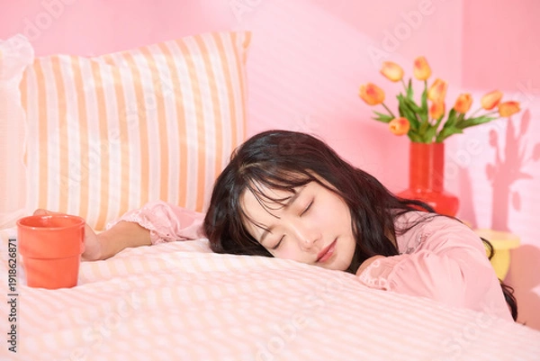 Obraz ピンク背景の部屋でリラックスするアジアの若い女性のポートレート