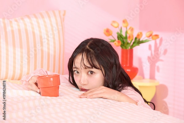 Obraz ピンク背景の部屋でリラックスするアジアの若い女性のポートレート
