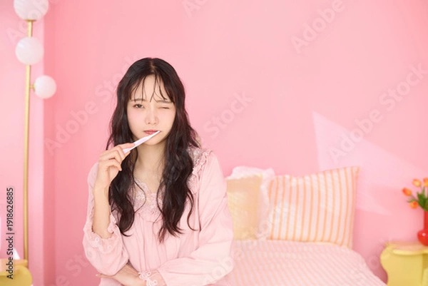 Obraz ピンク背景の部屋でリラックスするアジアの若い女性のポートレート