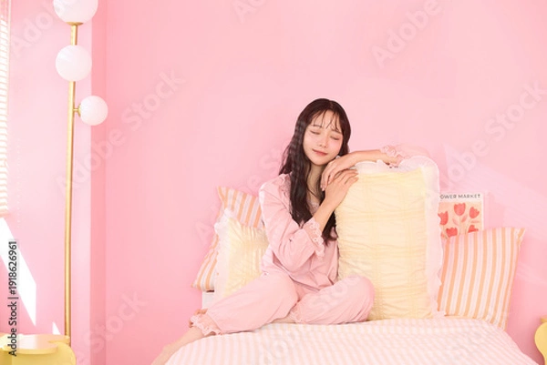 Obraz ピンク背景の部屋でリラックスするアジアの若い女性のポートレート