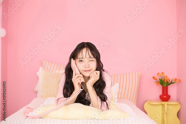 Obraz ピンク背景の部屋でリラックスするアジアの若い女性のポートレート