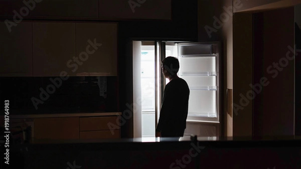 Obraz 机とキッチンの光の前に立つ人物シルエット