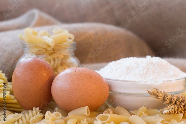 Fototapeta Dry spaghetti pasta tied up with rope and burlap bag of wheat grains