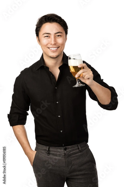 Fototapeta Happy smiling man in a black shirt and pants, holding a great cold beer in his hand with a big smile on his face. White background.