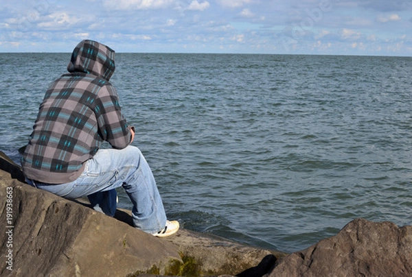 Obraz man thinking on a rock staring out into ocean