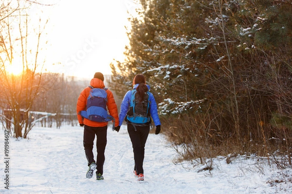 Fototapeta Romantic picture from back of man and woman with backpacks in winter