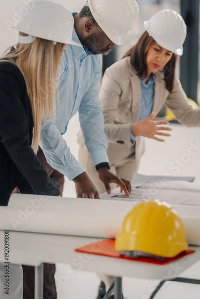 Fototapeta Engineering team collaborating on construction project blueprints