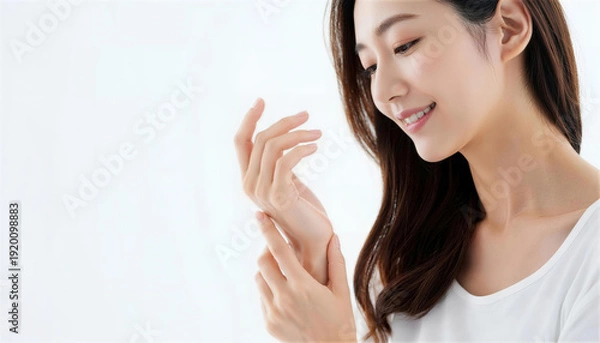 Obraz 手の甲に触れて肌の潤いを確認して微笑む若い女性