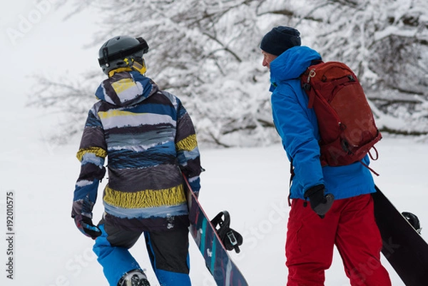 Obraz Two happy snowboarders is walking, talking and laughing