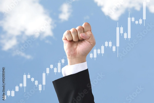 Fototapeta 株価が上昇し青空に向けてガッツポーズをするスーツを着た人物の手