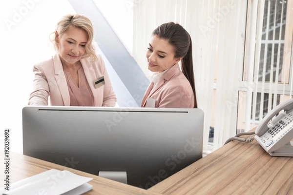 Obraz Female receptionist teaching trainee in hotel