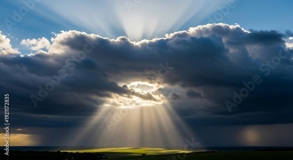 Fototapeta Dramatic sky with sun rays piercing through clouds over landscape