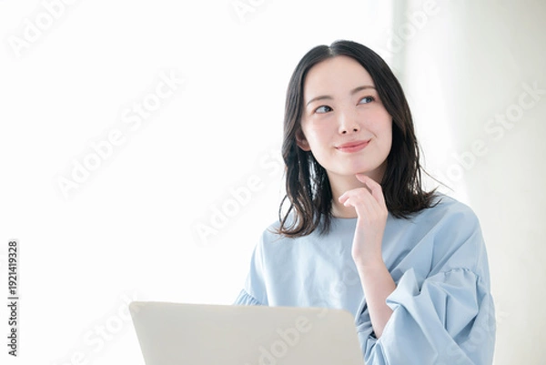 Obraz 明るい部屋でパソコンで仕事や検索、調べるお洒落な女性　資格や勉強などのスキルアップ、キャリアアップの前向きなポジティブイメージ顎に手を当てる考える悩む