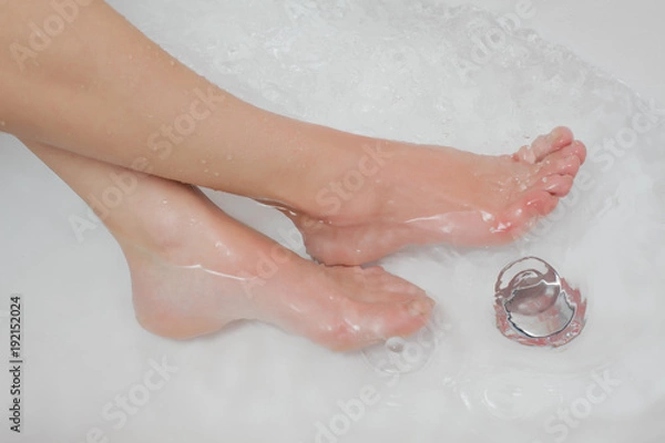 Fototapeta The woman resting her legs in the tub with water