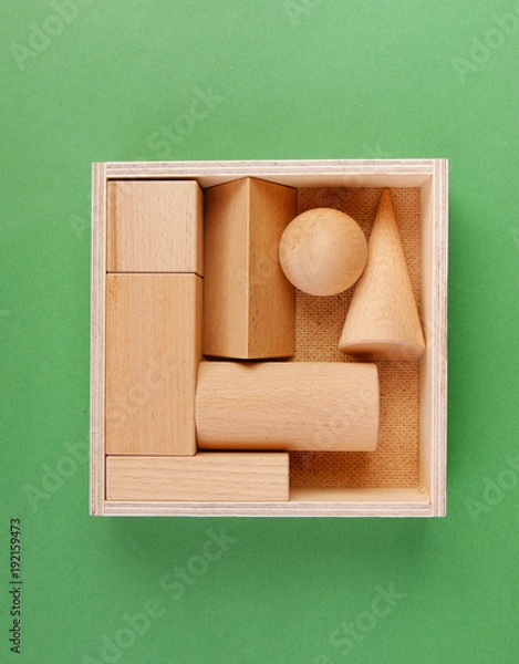 Fototapeta wooden geometric shapes in a box on a green background