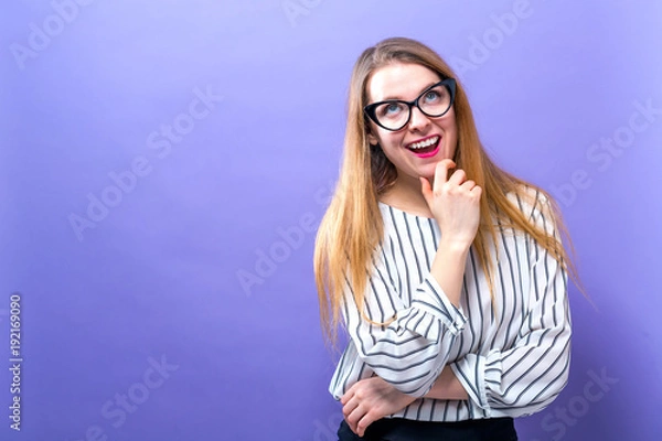 Fototapeta Young businesswoman in a thoughtful pose on a solid background