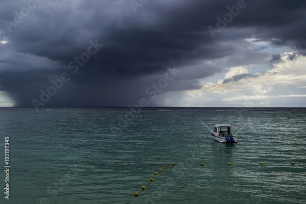 Fototapeta sea with anchoring boat and dark storm clouds on the horizon