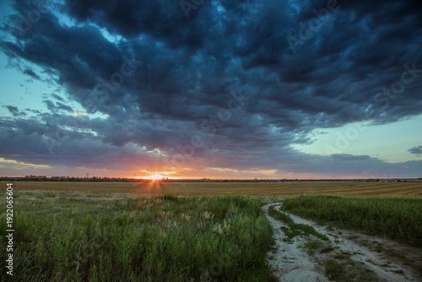 Obraz Dramatic Storm Clouds at Sunset over Rural Plains