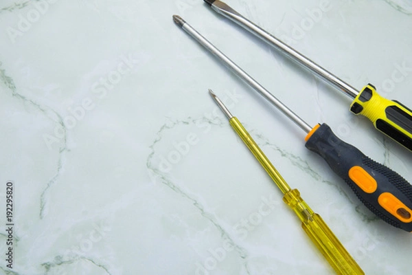 Fototapeta Home, House Repair, Redecorating, Renovating Concept. A set of repair tools on a white grid: three screwdrivers, top view, flat lay